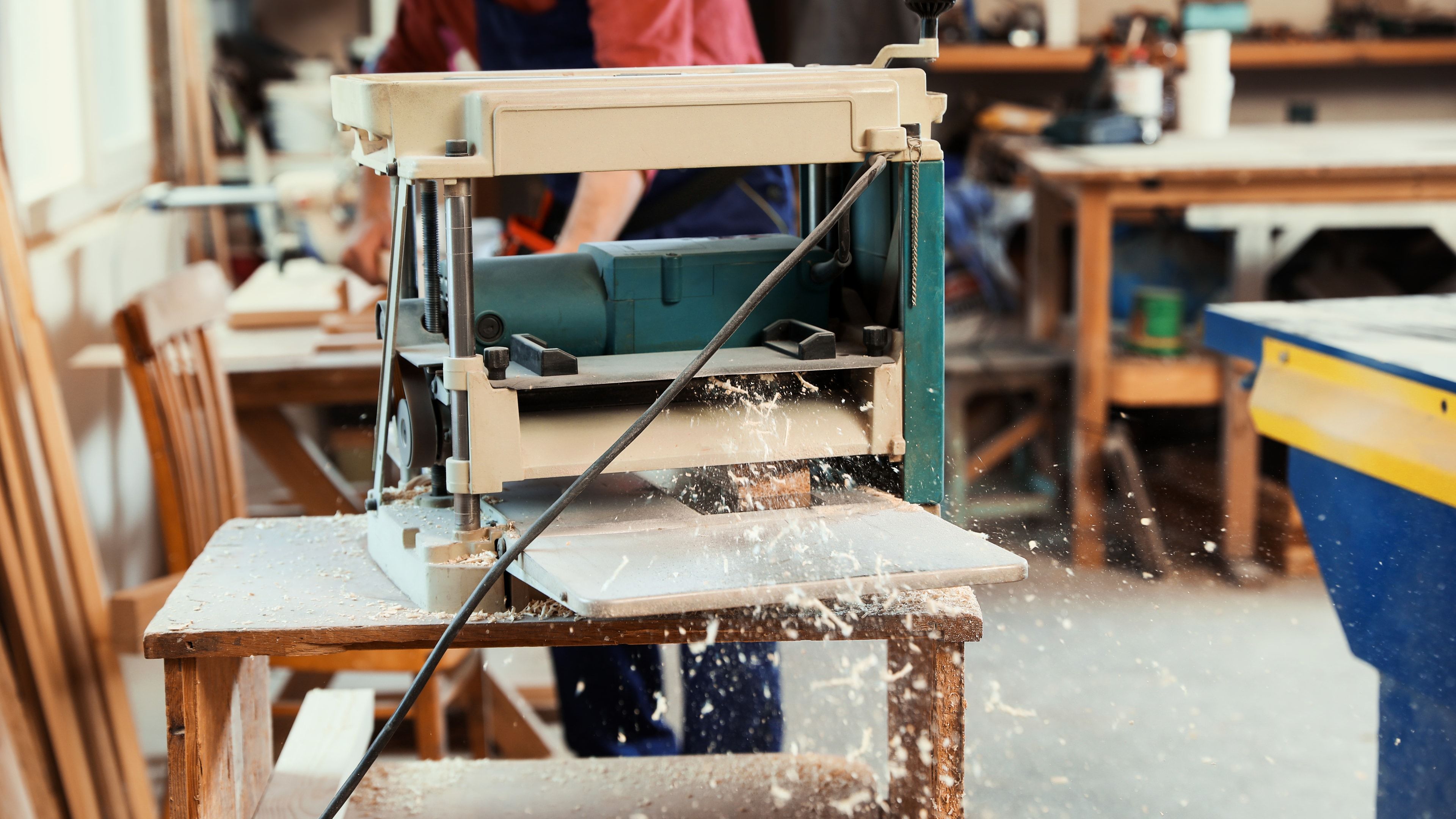 Regruesadora industrial cepillando tablón de madera maciza en taller